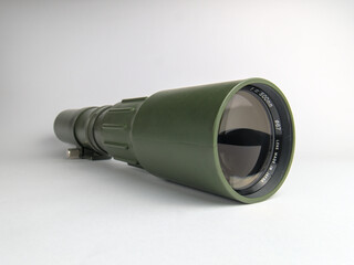 Vintage army green manual telephoto lens standing on a white background