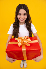 Fototapeta premium Happy teenager, positive and smiling emotions of teen girl. Teenager child in t shirt holding gift box on yellow isolated background. Gift for kids birthday. Summer holiday.