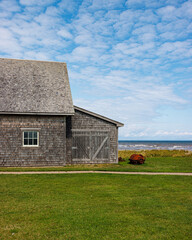 Partial view of grey building close to oceanfront coastline in summer with blue sky.