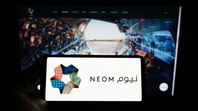 Stuttgart, Germany - 10-01-2022: Person holding smartphone with logo of Saudi Arabian property developer NEOM Company on screen in front of website. Focus on phone display.