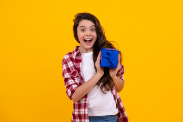 Amazed teenager. Child with gift present box on isolated background. Presents for birthday, Valentines day, New Year or Christmas. Excited teen girl.