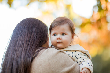 Beautiful young mother with a cute little girl 7 months old walks in the autumn park. Portrait of a...