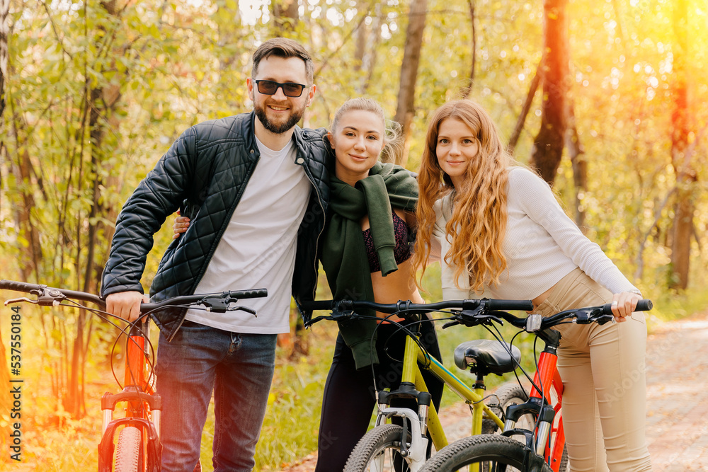 Wall mural Portrait group happy friends two woman and man cycling in autumn city park. Concept weekend active rest