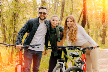 Portrait group happy friends two woman and man cycling in autumn city park. Concept weekend active rest