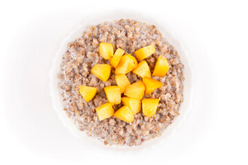 Buckwheat porridge with peach and milk in a bowl (plate) on a white isolated background. Porridge for a child (baby). Healthy breakfast. Template for the design.