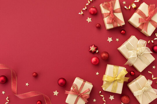 Christmas gift or present boxes and star confetti on red table top view. Greeting card with holiday decorations.