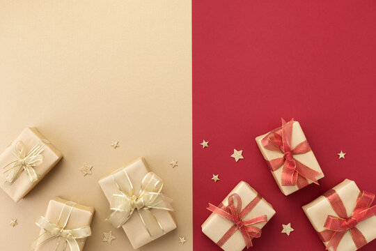 Christmas gifts or presents and star confetti on red gold background top view. Greeting card with holiday decorations.