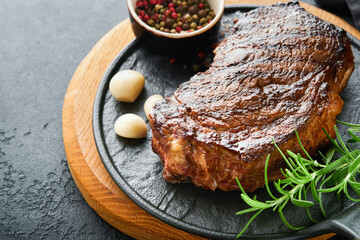Steaks. Grilled New York Steak with spices rosemary and pepper on black marble board on gray background. Top view. Mock up.