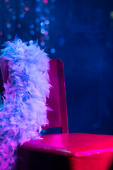 A red leather chair, a ribbon with boa feathers and a blue background with smoke before performing...