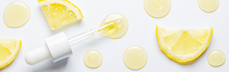 Drops of cosmetic serum and lemon slices. White background. Skin care product