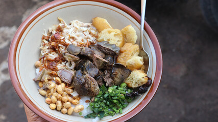 Bubur Ayam (Chicken Porridge), Indonesian Traditional Food Consist of White Rice Porridge, Shredded Chicken, peanut, Ati Ampela, Cake, and Spring Onion