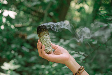 Herbal ritual incense stick burning. Fumigation ceremony with smudge of herbs for space energy cleaning. Ancestor spiritual shaman practice with white sage.