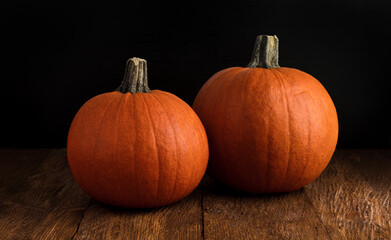 Two large orange whole mature pumpkins on a rustic wooden background, close-up. Concept of Halloween. Free space for text 