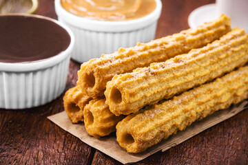 Fototapeta na wymiar churros, fried sweet with granulated sugar, filled with dulce de leche or creamy chocolate