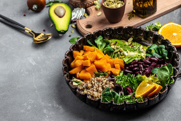 delicious quinoa salad with avocado, sweet potato, beans on gray background. place for text, top...