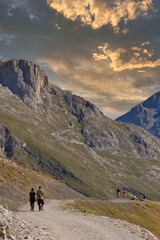Obraz premium Senderismo entre montañas al atardecer. Gente caminando en un valle