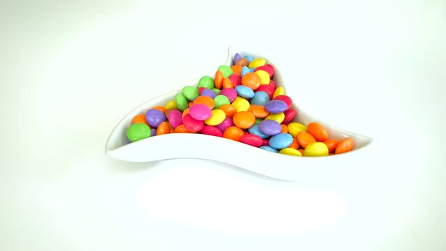Colourful chocolate candies dropped to the bowl