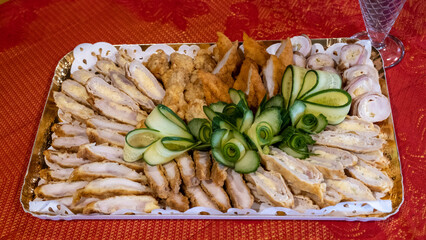 A plate of delicious seasoned chicken meat decorated with slices of fresh cucumber