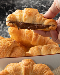 Holding French croissant stuffed with hazelnut. Selective focus.