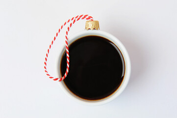 White cup of black espresso coffee decorated as Christmas ball. Close up, white background. New...