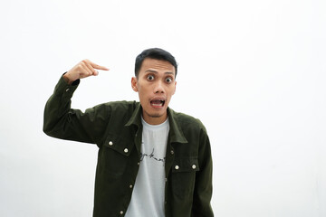 Asian man wearing green casual shirt angry while giving brain thinking gesture. isolated white background