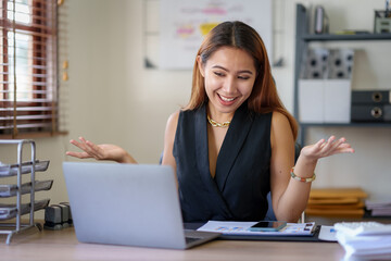 Beautiful young Asian woman college student is video chatting with her classmates using laptop, smiling faces and gestures happily studying.