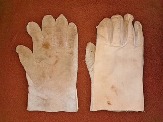 Work leather gloves, two, used and dirty, laid on a brown background