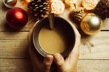 Christmas decorations and a hand holding a coffee cup on wooden table for background