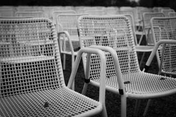 Rows of white metal garden chairs in front of an outdoor stage.