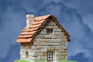 Casita hecha de ladrillos de piedra en miniatura con nubes de fondo	