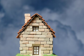 Casa  hecha de ladrillos de piedra en miniatura con nubes de fondo