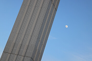 Abstract minimalist picture of riveted steel frame structure, part of the Elizabeth Bridge (Erzsébet híd) in Budapest, Hungary in front of blue sky and moon. 
Color architectural close-up detail photo