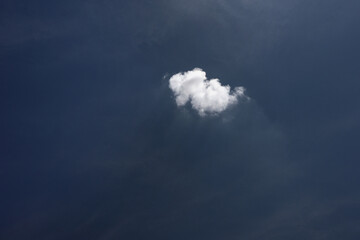 A single white cloud in the dark blue sky. Abstract minimalist sky landscape photo.