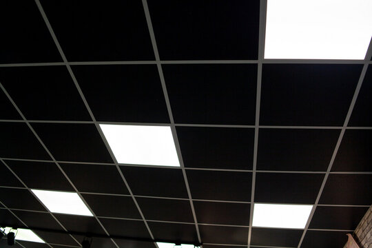 Black Ceiling With Neon Light Bulbs In Uprisen View. Fluorescent Light In Office Interior With Dark Ceiling.