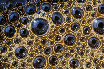 Close-up minimalistic, abstract photo of round bubbles of coffee's brown foam. Color macro surface photography.