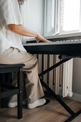 Woman playing music on synthesizer at home.