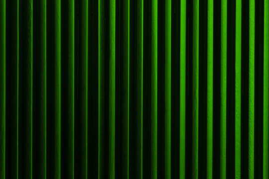 Minimalist abstract art picture: black pencils next to each other with green color light form vertical dark lines. Artistic, elegant design structure photo for graphics, background.