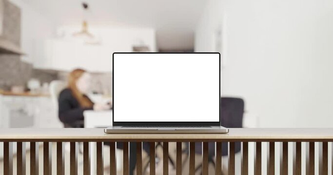 Laptop with blank screen on table smooth zoom in. home office background with working person, 4k 30fps