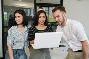 Three young business professionals standing together and discussing over business report in office hallway. Office colleagues revieving a business document on the tablet in coworking