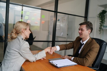Portrait of smiling young woman shaking hands with HR manager at job interview in office, copy space