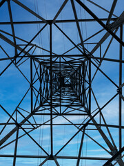 view from below of a high-voltage pylon with blue sky. Concept of high electricity and gas prices due to the economic crisis.