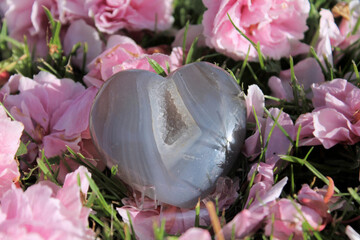 Agate heart and pink aragonite crystals  among stones and flowers