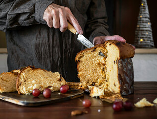 Front view of man cutting a panettone for Christmas dinner at home. Christmas candy.