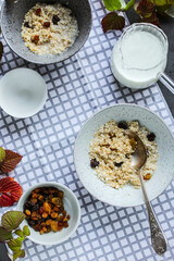 Oatmeal with raisins and frozen berries on a dining table with a checkered napkin.