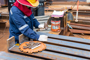 Workers use a hammer to stamp characters and numbers with steel hand stamps on steel structure beams for identification workpieces.