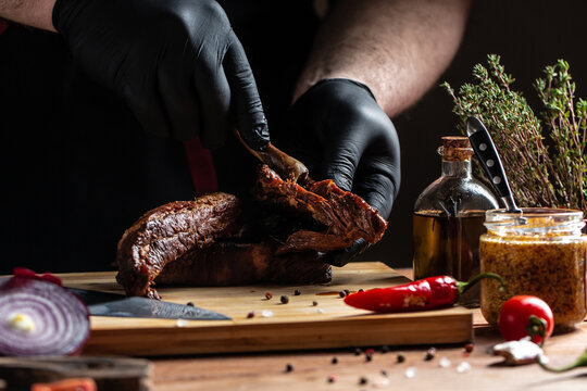 The chef in black gloves Grilled pork ribs on the kitchen. American food concept. fast food meal. banner, menu, recipe, place for text