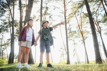 Little boy and girl go hiking on a forest road