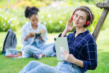 A young girl reading a book in a school park . An African student wearing glasses carrying a reading bag. Education, summer vacation. woman reading a book in the park