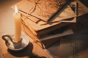 Photography in retro style. Ancient books and manuscripts on the table in the light of a candle.