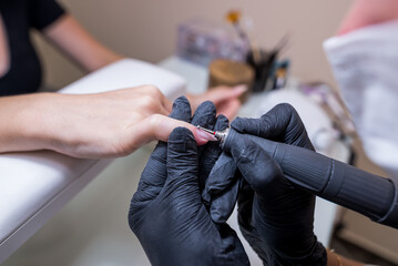 Manicurist makes a manicure to a client girl in a beauty salon.